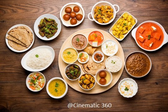 Overhead flat lay food photography of a traditional North Indian thali and vegetarian feast on a rustic wooden table by Cinematic360.