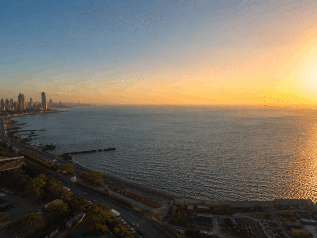 Aerial drone view of luxury residential towers, under-construction high-rise buildings, and panoramic Arabian Sea views in Mumbai.