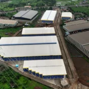 Aerial drone view of a massive industrial warehouse and logistics park development in Bhiwandi, Mumbai, showcasing commercial real estate infrastructure planning and site layout for a developer launch blueprint.
