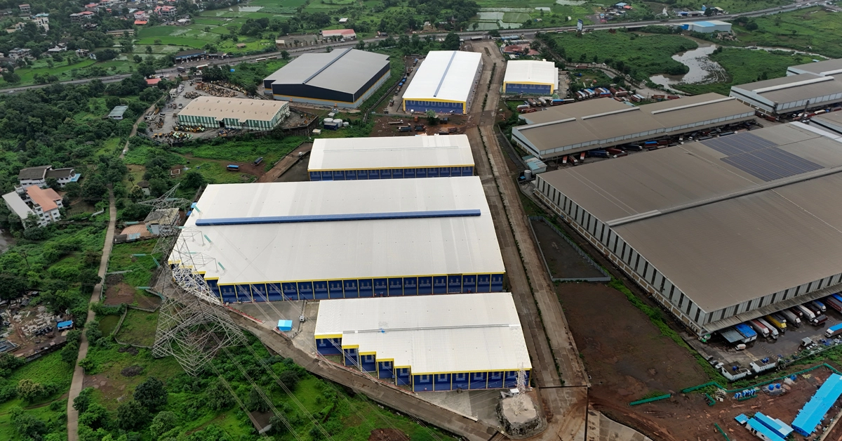 Aerial drone view of a massive industrial warehouse and logistics park development in Bhiwandi, Mumbai, showcasing commercial real estate infrastructure planning and site layout for a developer launch blueprint.