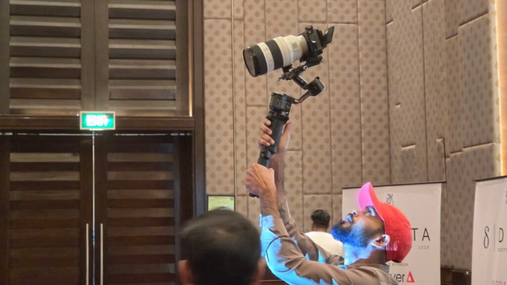 Cinematic360 operator composing live shot with telephoto zoom lens on 3-axis gimbal at corporate indoor event