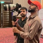 Cinematic360 cinematographer performing overhead gimbal sweep in hotel ballroom with crystal chandelier as dominant practical light source