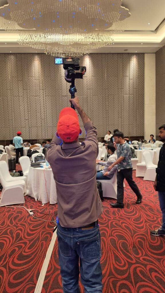 Cinematic360 cinematographer with gimbal raised in full overhead periscope hold at indoor corporate event with telephoto lens