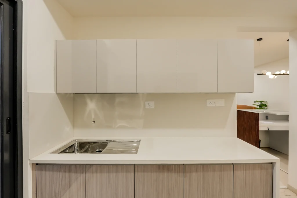 High-gloss modular kitchen upper shutters and white quartz countertop with stainless sink — reflection controlled at 45-degree camera angle — Cinematic360 Mumbai