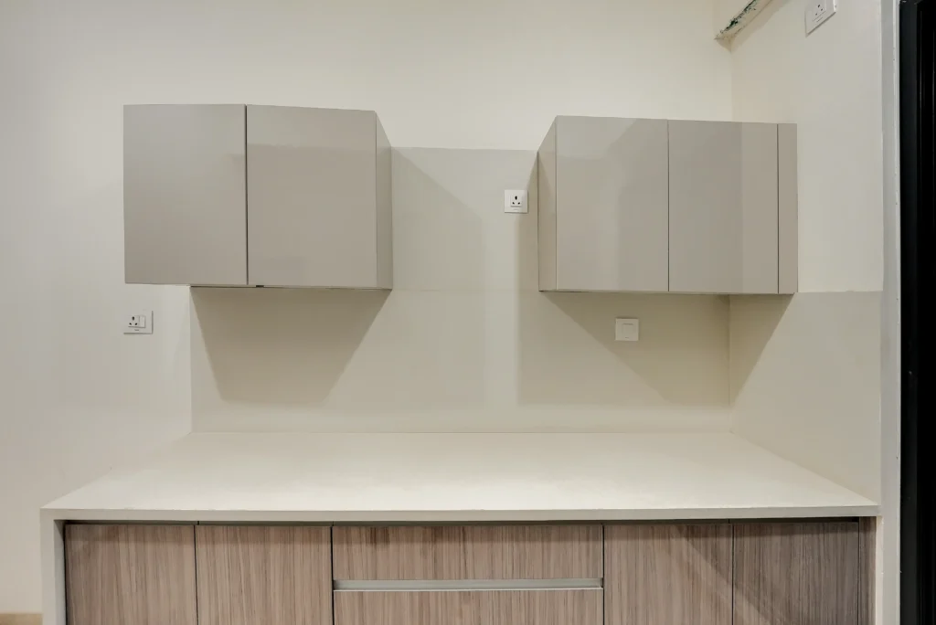 Text: High-gloss modular kitchen upper shutters and white quartz countertop with stainless sink — reflection controlled at 45-degree camera angle — Cinematic360 Mumbai