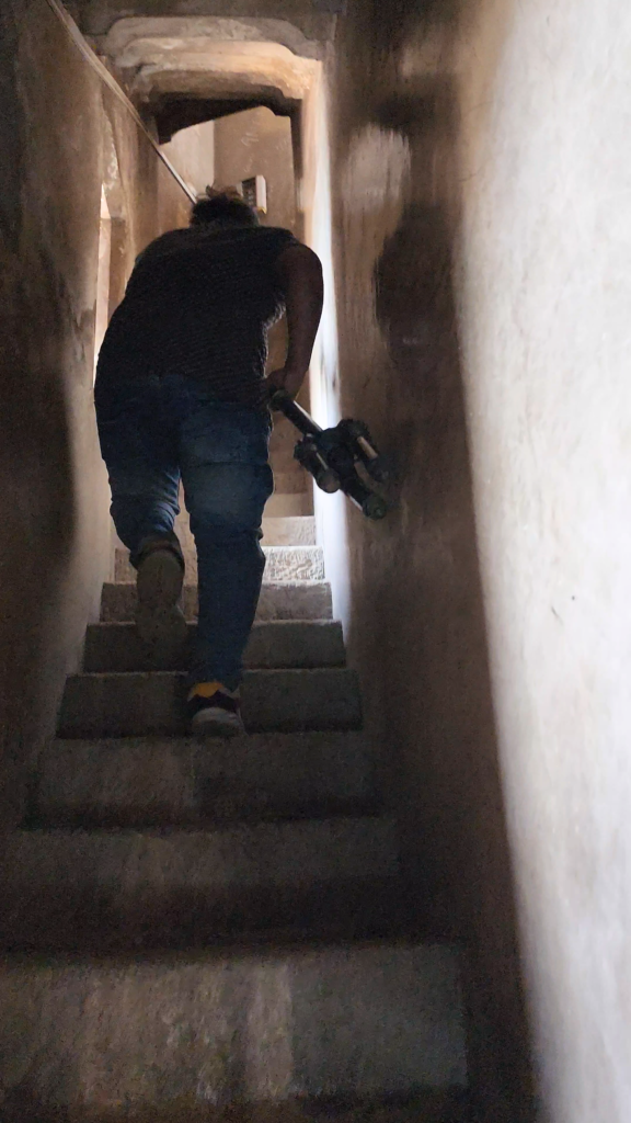 Crew carrying an Insta360 Pro 2 camera setup through a narrow staircase at CSMT Mumbai