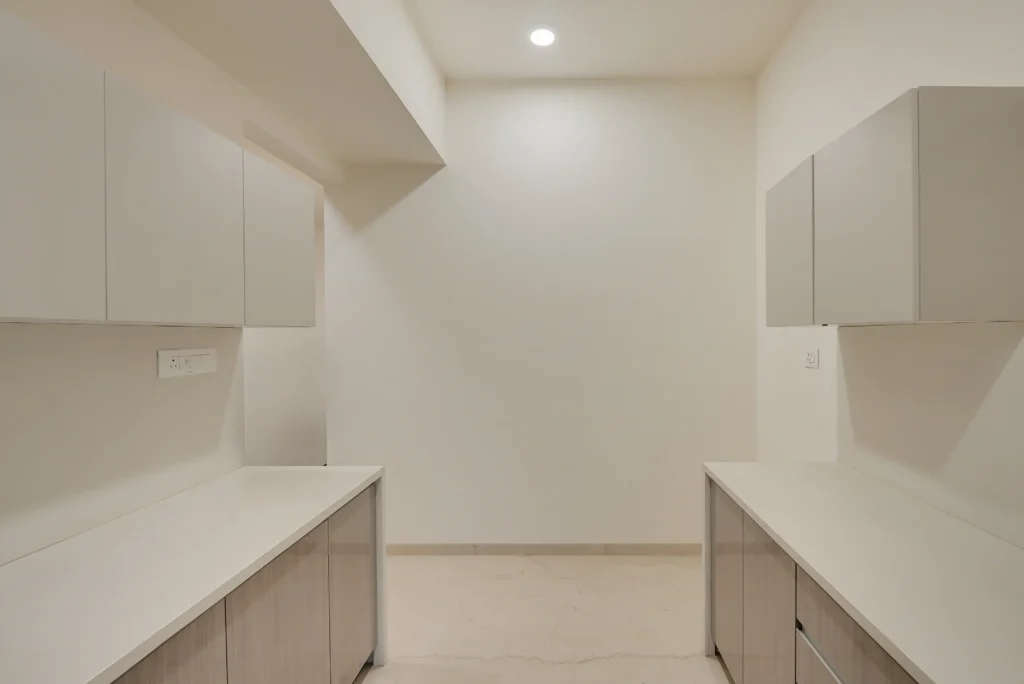 Full parallel modular kitchen with black-framed window at end wall showing cleared countertops and leading lines — Cinematic360 Mumbai